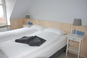 1 dormitorio con 2 camas con sábanas blancas y mesita de noche en Meine ECKE 1 en Eckernförde