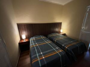two beds in a room with two lamps on tables at Olespier Hostel in Arequipa