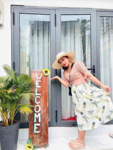 a woman wearing a hat standing next to a sign at Yến Homestay in Phước Hậu