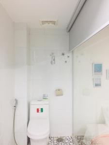 a white bathroom with a toilet and a shower at Yến Homestay in Phước Hậu