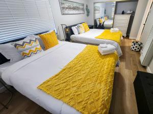two beds in a room with yellow and white sheets at Relaxing Cozy Back House with Backyard in Upland
