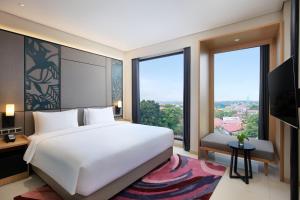 TanjungredepにあるMercure Berauの大きな白いベッドと大きな窓のある寝室