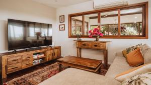 a living room with a couch and a television at Port Douglas Alamanda Estate w Ocean Views & Pool in Craiglie