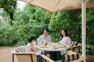 a family sitting at a table under an umbrella at The Westin Tokyo in Tokyo