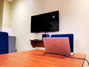 a laptop sitting on a table with a tv at Résidence Romacy, appartement 2 chambres avec balcon à Ahala, quartier résidentiel de Yaoundé in Yaoundé