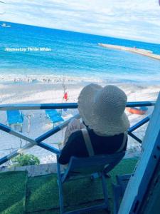 a person sitting in a chair looking at the beach at Homestay Thiện Nhân 