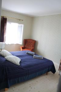 a bedroom with a blue bed and an orange chair at Trepimäe Guest Apartment in Viljandi