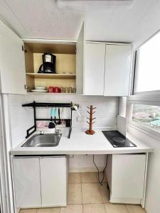 Una cocina con gabinetes blancos y un fregadero y una ventana. en Lakbay Philippines, en Baguio