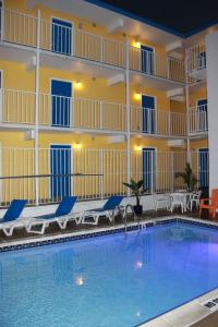 a pool in front of a hotel with chairs and a building at Seaside Inn & Suites in Fenwick Island