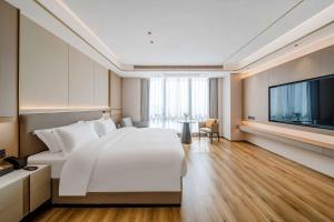 ShundeBodun International Apartment Foshan Shunde Fengjian Water Village Branch的卧室配有一张白色大床和一台平面电视。