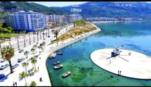 a beach with palm trees and boats in the water at Diego Rooms Vlora in Vlorë