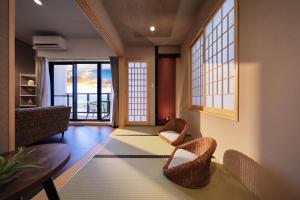 a living room with chairs and a table and windows at クリスタル別荘南城 in Nanjo
