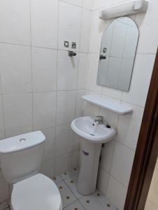 a bathroom with a toilet and a sink and a mirror at Résidence Romacy, appartement 2 chambres avec balcon à Ahala, quartier résidentiel de Yaoundé in Yaoundé
