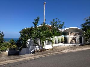 a white fence in front of a house at A Seascape Guest Room in Fajardo