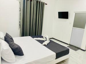 ein Schlafzimmer mit einem weißen Bett, auf dem ein Stofftier liegt in der Unterkunft Hotel Jay R in Trincomalee