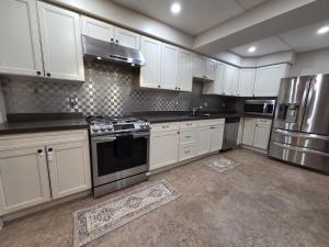 a kitchen with white cabinets and stainless steel appliances at Three Bedrooms House in Mississauga with free parking Conveniently located with easy access to the airport downtown Toronto major malls and highways for a seamless stay in Mississauga