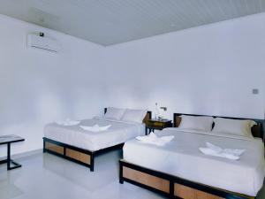 two beds in a room with white walls at Vaniglia House Tetebatu in Tetebatu