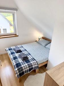 a bedroom with a bed with a plaid blanket on it at Domki Potok - Noclegi Bieszczady in Stefkowa