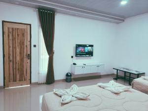 a room with two beds and a television in it at Vaniglia House Tetebatu in Tetebatu