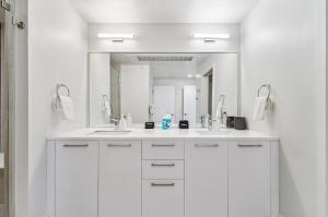 a white bathroom with two sinks and a large mirror at The Penthouse | Espadin LoHi in Denver +32 photos