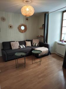 a living room with a black couch and two tables at Appartement spacieux en centre ville de Besse in Besse-et-Saint-Anastaise