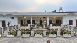 a large white building with potted plants in front of it at Khurja Wali Dharamshala in Rishīkesh