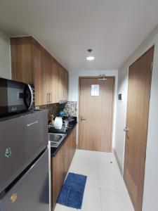 a kitchen with wooden cabinets and a refrigerator at Aldo mall of Asia condotel in Manila +20 photos