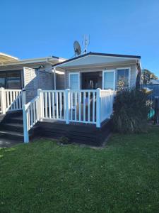 a house with a porch with a white fence at Monarch Studio in Athenree