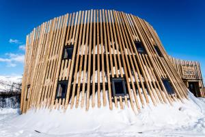 um edifício de madeira está coberto de neve em Enoks i Láddjujávri em Nikkaluokta