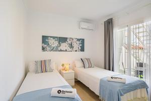 two beds in a room with a window at Stay Belonio El Palo Beach in Málaga