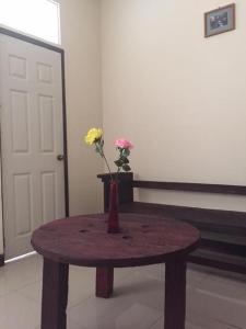 a wooden table with a vase with flowers on it at Alojamiento D'Rosales in Cobán