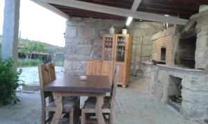 a stone kitchen with a wooden table and a fireplace at Quinta do Mineiro-Serra da Estrela in Matança