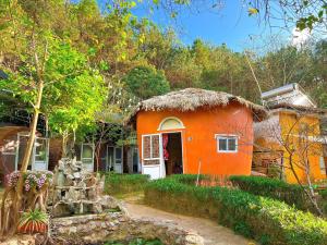a small orange house with a thatch roof at Mộc House in Mộc Châu