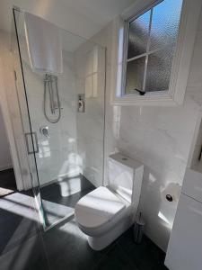 ダニーデンにあるSunny Waterfront Apartmentのトイレとシャワー付きの白いバスルーム +7枚の写真