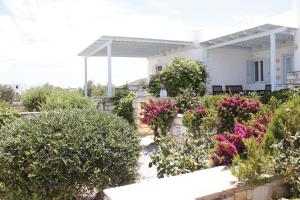 a garden in front of a white house with flowers at Ambelas Mare Apartments in Ambelas