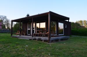 una pequeña cabaña con mesas de picnic en el césped en SaulesKempings, en Mērsrags