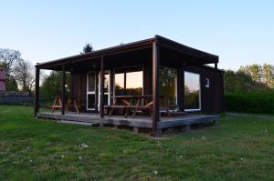 a small cabin with picnic tables in the grass at SaulesKempings in Mērsrags