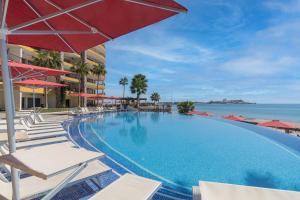 a large swimming pool with chairs and an umbrella at Sonoran Sky in Puerto Peñasco