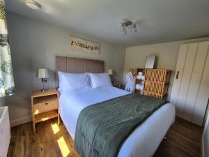 a bedroom with a large white bed and a night stand at Birch Banc Retreats - Bedw in Llanidloes