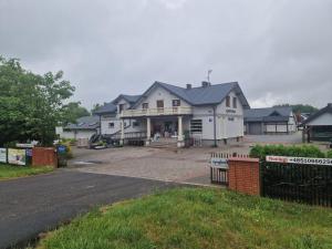 a large white house with a driveway in front of it at Agrocentrum in Kobylany