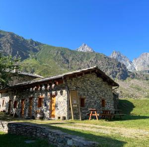 a stone building with mountains in the background at Agriturismo Baita Stella in Crissolo