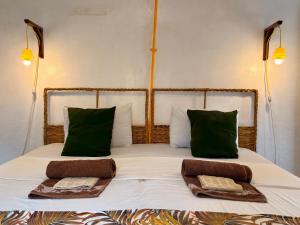 un letto con cuscini verdi e due asciugamani di Hera Hostel Diani a Diani Beach Altre 25 foto