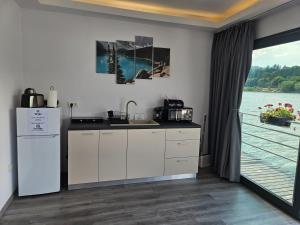 a kitchen with a sink and a refrigerator next to a window at Sia Lake View Bicaz in Ceahlău
