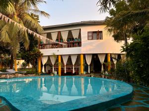 un hotel con piscina di fronte a un edificio di Hera Hostel Diani a Diani Beach