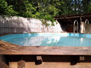 a swimming pool with a wooden table in front of it at Le Domaine De La Genette in Paussac-et-Saint-Vivien
