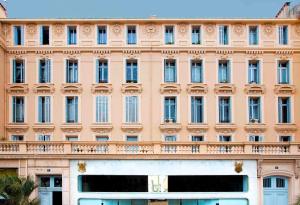 Edificio grande de color rosa con balcón en Residence du Louvre - LRA Cannes, en Cannes