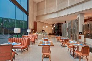 a restaurant with tables and chairs and large windows at Kochi Marriott Hotel, LuLu International Shopping Mall in Cochin