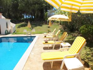 a group of chairs and umbrellas next to a swimming pool at Casa Camelia in Vilamoura