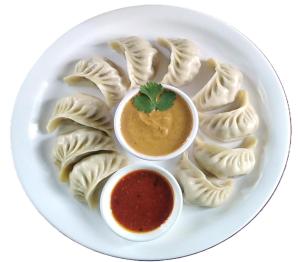 a plate of food with dumplings and a dipping sauce at Kankali Viewpoint Resort Pvt Ltd in Kathmandu +24 photos