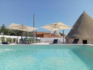 a swimming pool with two umbrellas and a house at Al Settimo Chilometro in Gioia del Colle